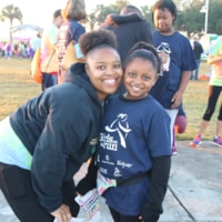 Girls on the Run participant holding program 5K medal with coach.